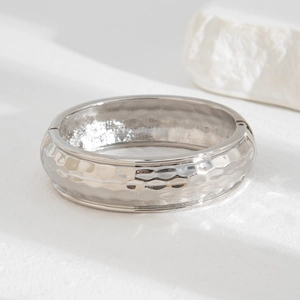 Minimalist silver hammered metal bangle bracelet with geometric texture and side clasp