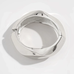 Detalle de brazalete ancho de plata con corte geométrico irregular y acabado pulido