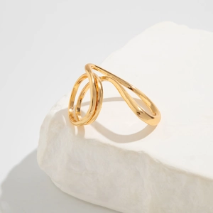 Detail of a polished gold-plated multi-layer wave ring displayed on a natural stone base