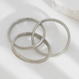 Detailed view of silver spring-coil stackable bracelets featuring a set of three metal bangles