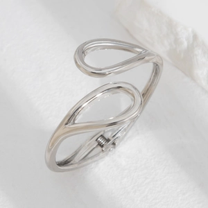 Macro view of silver-toned irregular wave hinge bracelet with drop-shaped overlap