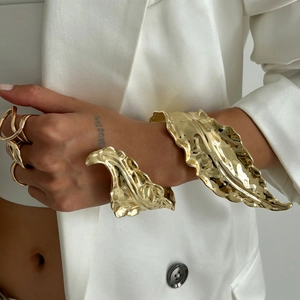 Detail of liquid leaf-shaped gold cuff bracelet and matching ring on female model