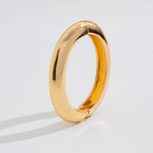 Detailed side view of a chunky gold alloy bangle with high-polish mirror finish