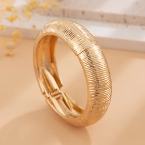 Gedetailleerde close-up van gouden gelaagde armband met textuur van horizontale ribbels