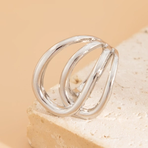 Detail shot of a silver layered irregular open bracelet on a beige natural stone base