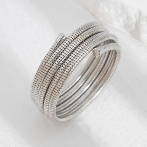 Macro view of silver-tone multi-layer spiral Tubogas bracelet on a textured stone base