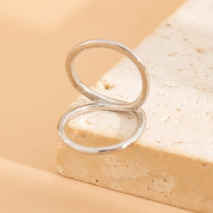 Detailed view of intertwined silver double ring set on a natural stone base