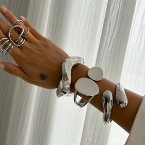 Detailed view of silver fluid metal bracelet and ring set with polished mirror finish
