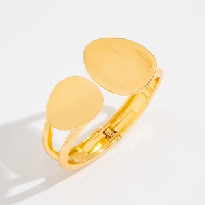 Detailed view of golden metal cuff bracelet featuring a hinge design and oval ends