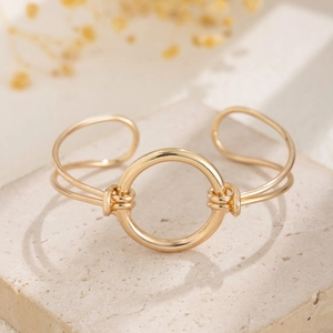 Macro detail of golden cuff bracelet with geometric ring and knotted wire on stone base