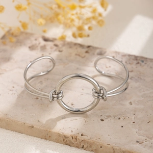 Close-up of a silver open cuff bracelet with a large ring and knot detail on stone