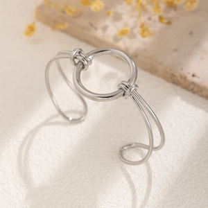 Close-up of a silver geometric open bangle with a large ring and minimalist knot detail
