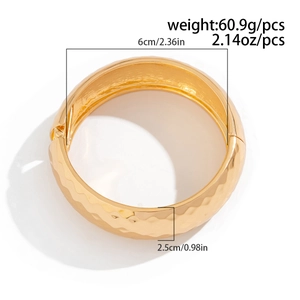 Detalle de brazalete dorado con patrón martillado y medidas de cierre de bisagra