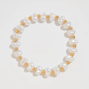 Detail of beaded bracelet featuring irregular white pearls and smooth golden metal beads