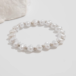 Detailed view of baroque pearl bracelet with silver beads on minimalist stone background