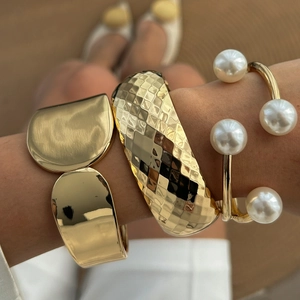Set de tres pulseras rígidas doradas gruesas y un brazalete abierto con grandes perlas blancas