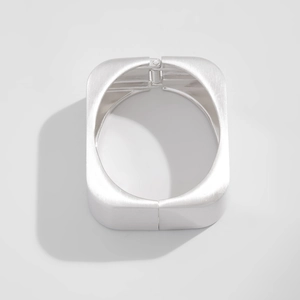 Detailed view of wide silver metal bracelet with hinge and brushed texture surface