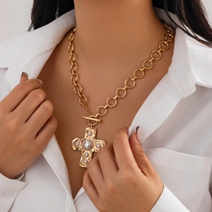 Detail of gold cross pendant with pearls and toggle clasp on a thick link chain necklace