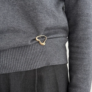 Lava liquid gold metal brooch styled as a waist cincher on a grey knit sweater