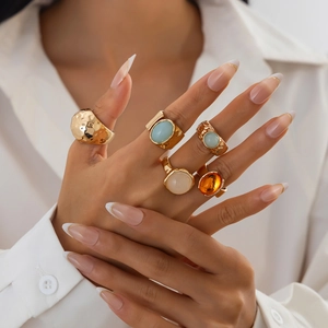 Detail of 5-piece gold-tone ring set featuring colorful acrylic stones on hand