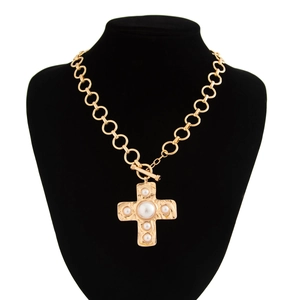 Detail van vloeibaar metaal gouden kruis hanger ketting met imitatieparels op fluwelen display
