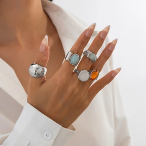 Close-up of stacked alloy rings with acrylic gemstones on model in white shirt
