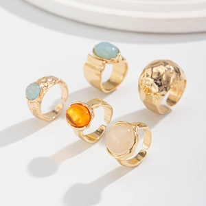 Set of five gold rings featuring translucent oval gems in blue, orange, and cream colors