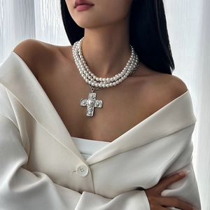 Detailed close-up of a triple-strand pearl choker with a textured silver cross pendant