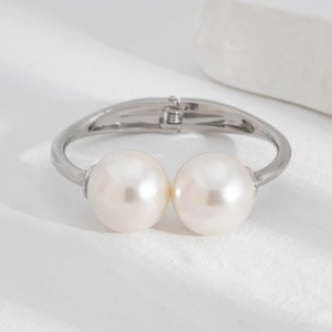 Detailed view of silver spring bracelet featuring two large glossy pearls on a white stone