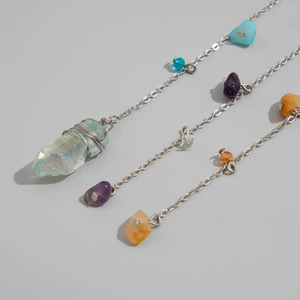 Macro view of natural crystal stones and silver-tone chain on a minimalist gray background