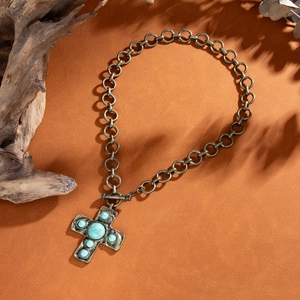 Close-up of vintage bronze cross necklace with turquoise stones and OT toggle clasp