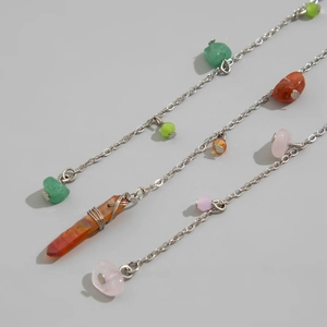 Macro view of bohemian handmade stone beaded chain with a wire-wrapped orange crystal pillar