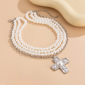 Detailed macro view of triple-layered pearl necklace with a vintage silver cross pendant