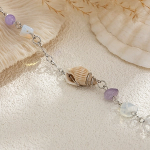 Détail d'une pince à cheveux en coquillage avec gravier violet et pompon en perles