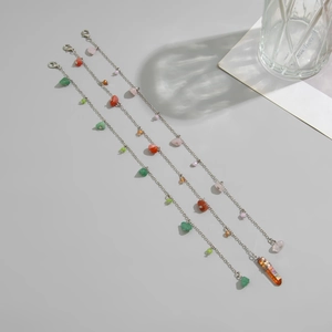 Close-up of three silver-plated chains with colorful crushed stones and a crystal pendant