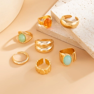 Detail of 7-piece gold alloy ring set with orange and green resin stones on stone plate
