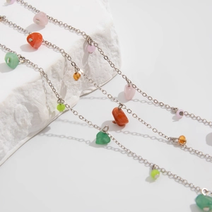 Detail of silver chain necklaces with colorful semi-precious stone pendants on white stone