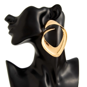 Detailed view of large gold-tone irregular textured metal earrings on a black bust model