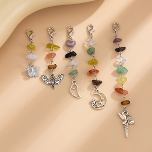 Detail of five assorted silver alloy charms with natural gemstones on a soft beige fabric