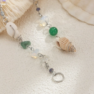 Vue macro d'une pince à cheveux en coquillage avec perles de jade et franges d'opale