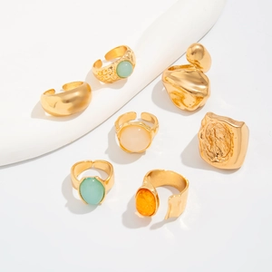 Macro detail of 7 vintage gold alloy rings with colorful resin stones on white background