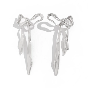 Detailed view of glossy silver ribbon bow earrings with a polished mirror finish surface