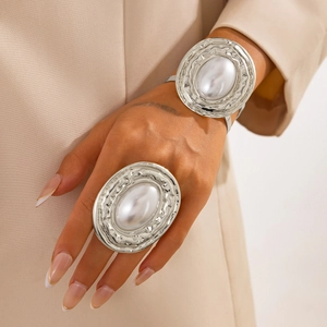 Dettaglio di bracciale rigido in argento strutturato e anello con perla su modella