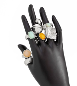Close-up of chunky silver rings set with colorful gemstones on a black hand model