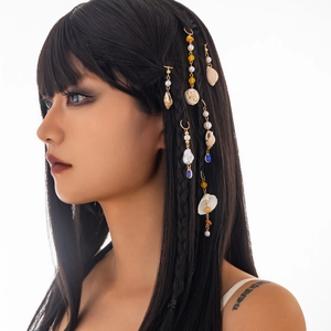 Detail of seashell and pearl hair accessories on a model with braided black hair