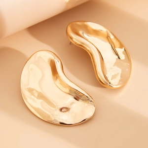 Detailed macro view of liquid metal gold teardrop earrings with hammered texture and mirror finish