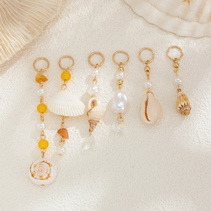 Detail of beach hair clips with natural shells, pearls, and yellow beads in gold plating
