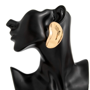 Detailed view of irregular polished gold pea-shaped earrings on a black mannequin