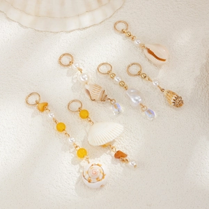 Detailed close-up of bohemian ocean style hair rings featuring sea shells and pearls