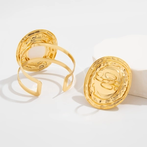 Dettaglio macro del bracciale rigido dorato martellato con trama metallica su pietra